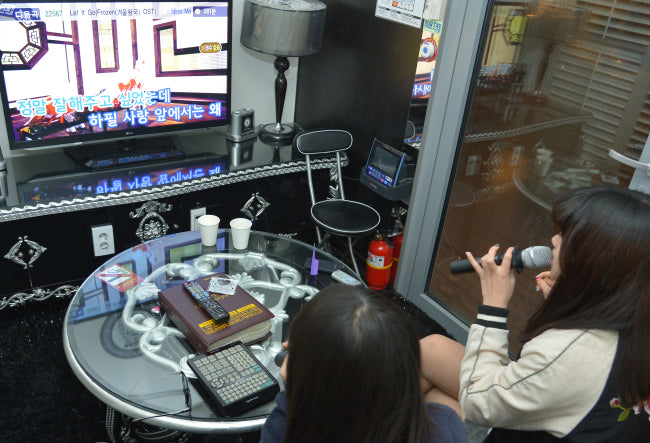 Two women singing inside a Korean noraebang karaoke room in Hongdae, Seoul