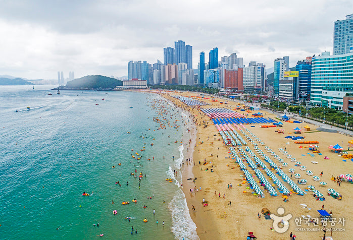 Busan's Haeundae Beach with blue ocean and golden sand, the kind of seaside scenery featured in LOONA ViVi's Everyday I Love You music video