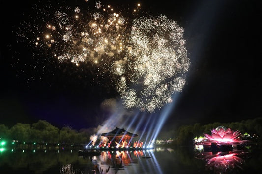 Pink and white lotus flowers in full bloom filling Gungnamji Pond in Buyeo Chungcheongnam-do with a traditional wooden bridge leading to the Poryongjeong pavilion in the background during the Buyeo Seodong Lotus Festival