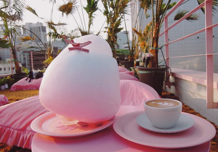 Bright pink Pool Cafe at Stylenanda Pink Hotel with palm trees and sunbed seating around a signature pink pool centerpiece in Seoul