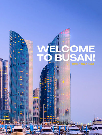 Modern skyscrapers with 'Welcome to Busan!' text against a blue sky.